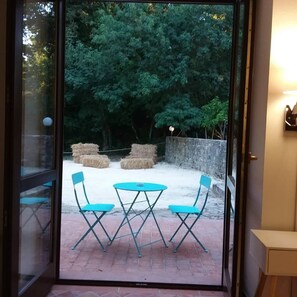 A patio with a table and chairs, hay bales, and a stone wall. - Chiosi Country Club (Corleone)