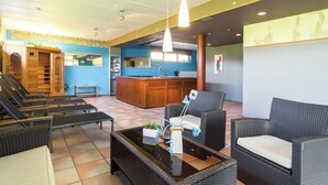 Una hall d'albergo con reception, poltrone e tavolino.