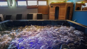 Una vasca idromassaggio con getti d'acqua in una stanza con armadietti in legno e finestre.