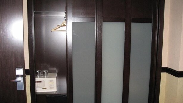A dark wooden door with frosted glass panels and a small shelf with a white object and a glass. - Hotel Machaco (Alburquerque)
