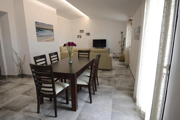 Un espace de vie moderne comprenant un coin repas avec une table et des chaises, un canapé et un téléviseur.