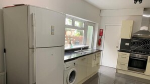 A compact kitchen with a refrigerator, washing machine, sink, and stove. - Wellfield Blooms Cardiff Romantic Room (Cardiff)