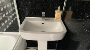 A bathroom with a white sink, a toilet, and a shower area. - Wellfield Blooms Cardiff Romantic Room (Cardiff)