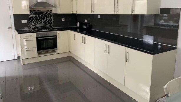 A modern kitchen with white cabinets, a black countertop, and stainless steel appliances. - Wellfield Blooms Cardiff Romantic Room (Cardiff)