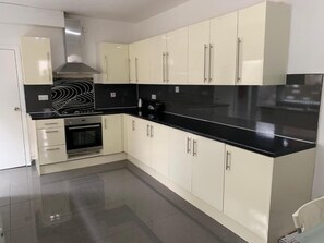 A modern kitchen with white cabinets, a black countertop, and stainless steel appliances.