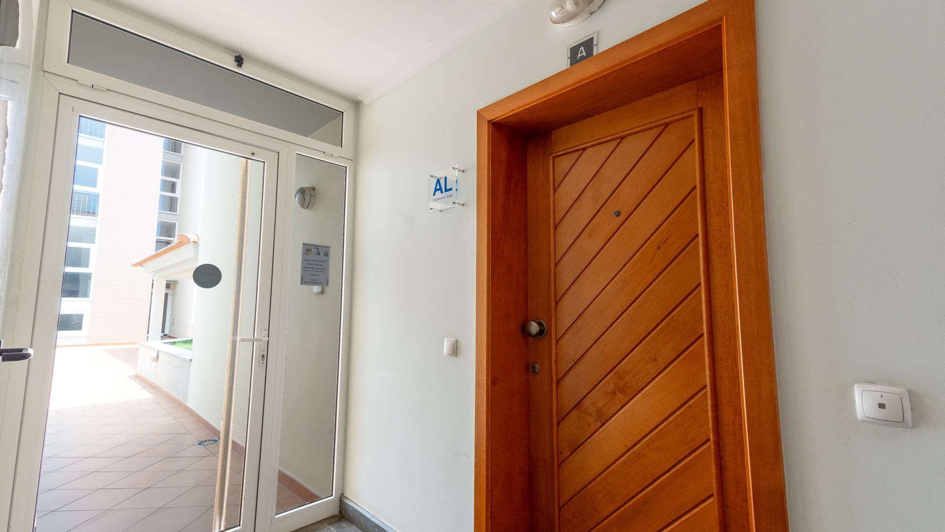 Un couloir avec une porte en bois, un mur blanc et une pancarte indiquant le numéro de la salle A.