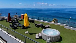 Une terrasse sur le toit avec des sièges extérieurs, un jacuzzi et une vue sur l’océan.