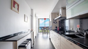 Een moderne keuken met uitzicht op zee, voorzien van een eethoek, zwarte aanrechtbladen en houten kastjes.