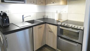 A compact kitchen with a microwave, sink, coffee maker, and double oven. - Charming 2-Bedroom Apt with Balcony, Mountain Views, WiFi, Parking & Baby Gear in St Lary Soulan (Vignec)