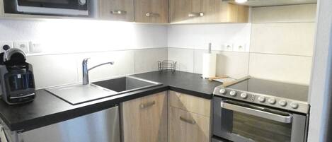 A compact kitchen with a microwave, sink, coffee maker, and double oven.