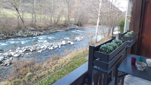 A balcony with a view of a river, surrounded by bare trees and mountains. - Charming 2-Bedroom Apt with Balcony, Mountain Views, WiFi, Parking & Baby Gear in St Lary Soulan (Vignec)