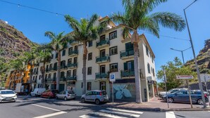 Un immeuble à plusieurs étages doté de balcons, d’un panneau indiquant un parking et une vue sur la rue.