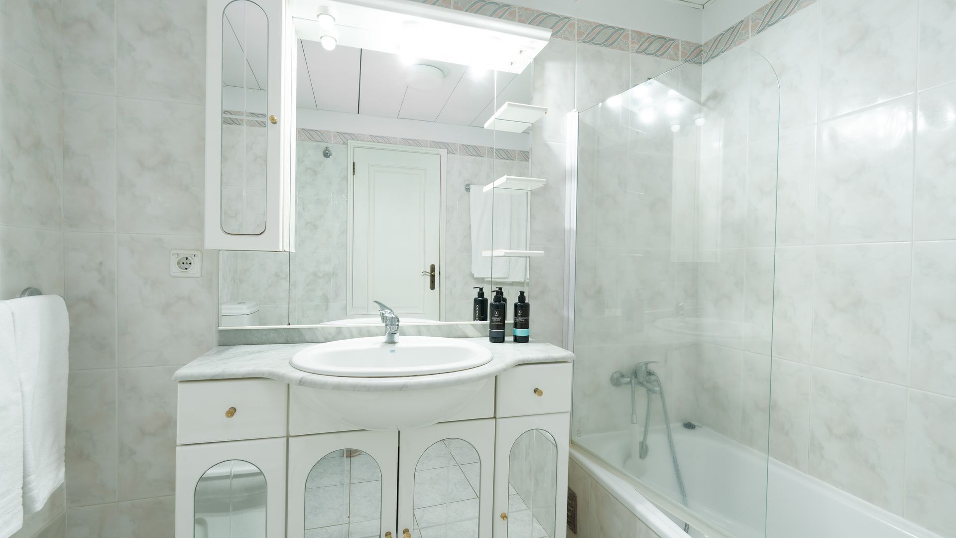 A bathroom with a white sink, mirror, and shower.