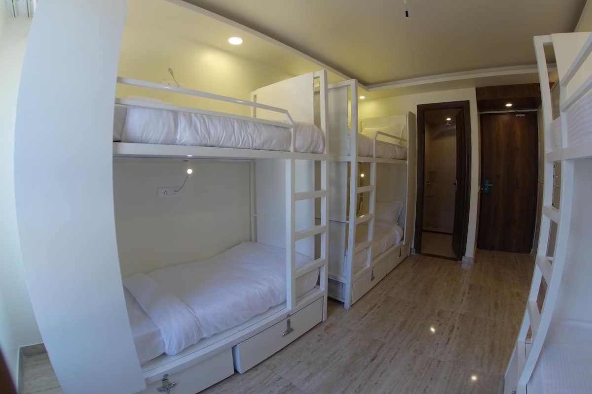 A bunk bed room with a wooden door and a white wall.