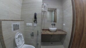 A compact bathroom with a toilet, a sink, a shower, and a mirror. - Backpacker Panda Rishikesh (Narendranagar)
