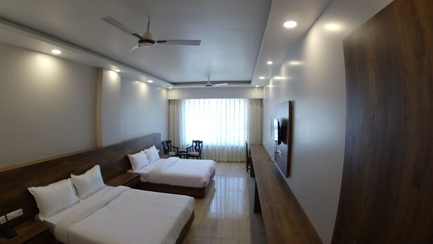 A hotel room with two beds, a ceiling fan, a TV, and a large wooden panel on the wall. - Backpacker Panda Rishikesh (Narendranagar)