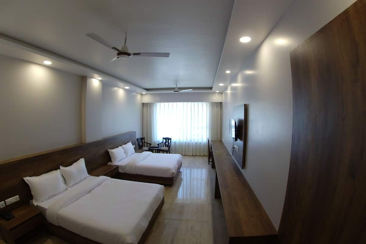 A hotel room with two beds, a ceiling fan, a TV, and a large wooden panel on the wall.