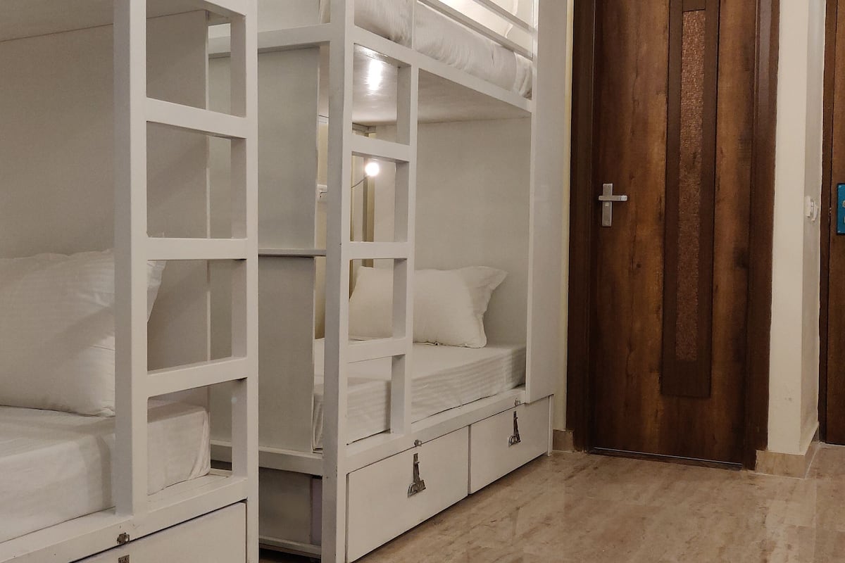 A room with bunk beds, a wooden door, and a tiled floor.