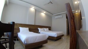 A hotel room with two beds, a wooden headboard, a ceiling fan, and an air conditioning unit. - Backpacker Panda Rishikesh (Narendranagar)