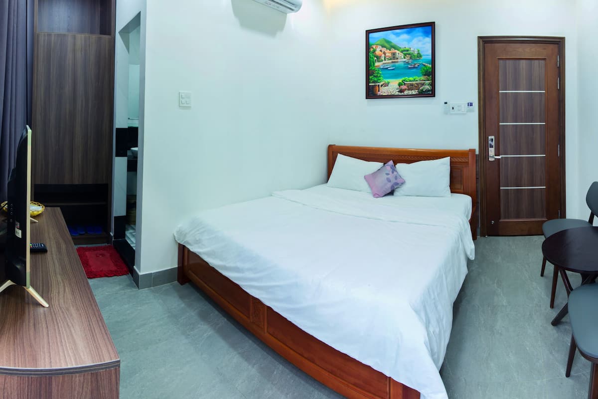 Une chambre d’hôtel avec un lit, un bureau avec un ordinateur, une chaise et une porte.