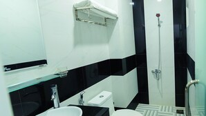 Un baño moderno con un lavamanos blanco, encimera negra y cabina de ducha con mampara de vidrio.