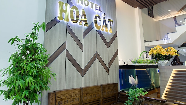 Zona de recepción de un hotel con diseño moderno, que incluye un cartel iluminado grande, un mostrador de recepción y una escalera.