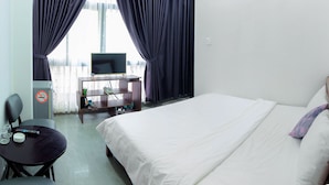 Una habitación de hotel con cama, escritorio, computadora, silla y televisor.