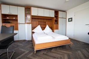 Quarto com cama, escrivaninha e armários embutidos.