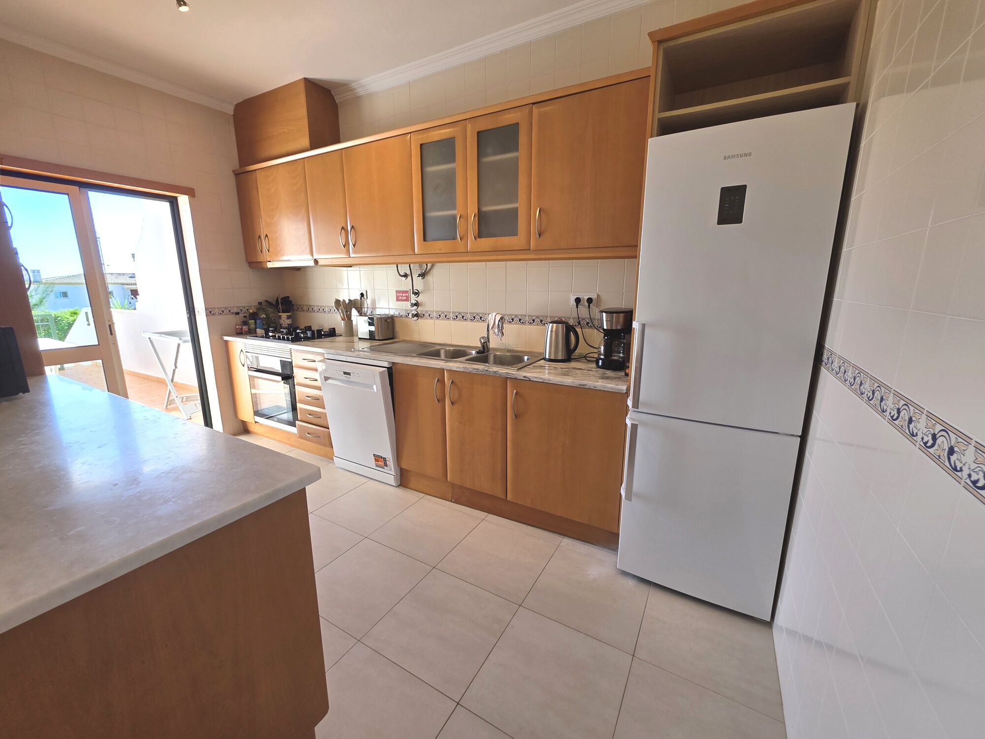 A kitchen with wooden cabinets, a white refrigerator, a dishwasher, and a countertop with various appliances.