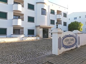 A modern building with a white facade, multiple balconies, and a cobblestone entrance. - Cristaluz in central location, 5 mins walk to shops, restaurants and the beach ! (Praia da Luz)