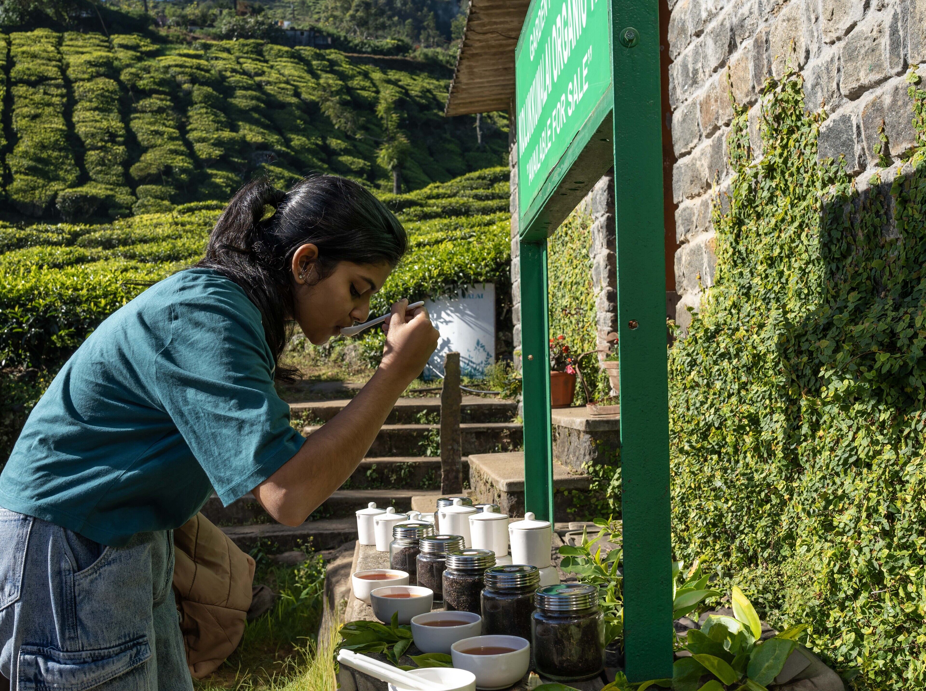 A person at a tea station with a sign indicating organic tea for sale.