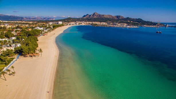 An aerial view of a coastal area with a sandy beach, clear blue waters, and a mountainous backdrop. - Finca Alcudia Sa Vinya Vella near beach with pool (Alcúdia)