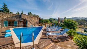 A pool area with a stone wall, lounge chairs, and a view of the landscape. - Finca Alcudia Sa Vinya Vella near beach with pool (Alcúdia)