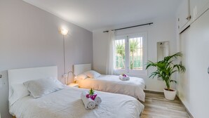 A hotel room with two beds, a potted plant, and a window with curtains. - Finca Alcudia Sa Vinya Vella near beach with pool (Alcúdia)