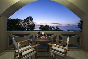 An outdoor balcony with a table set for two, overlooking a sunset view. - Kolimbito Sea Side (Kissamos)