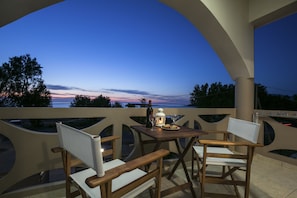 A balcony with a table and chairs, overlooking a scenic view of the sunset over the water. - Kolimbito Sea Side (Kissamos)