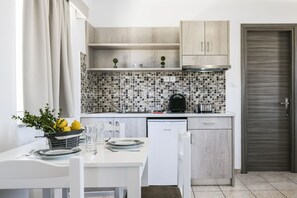A modern kitchen with white cabinetry, a tiled backsplash, and a dining area with a table set for two.