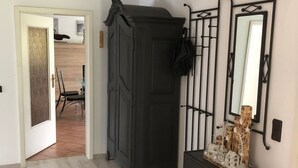 A room with a dark wooden wardrobe, a dresser, and a mirror on the wall. There is a door leading to another room and a light fixture on the ceiling. - Holiday house "Nordsee Pur" (Halbemond)