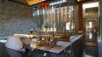 A modern interior with a glass partition, wooden furniture, and a brick wall.