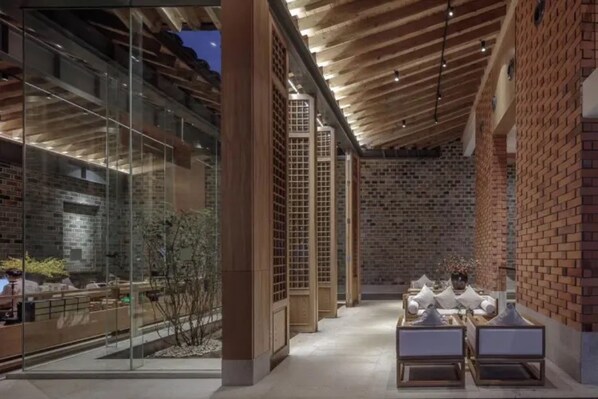 Un intérieur moderne avec une façade en verre, des poutres en bois et des murs en briques.