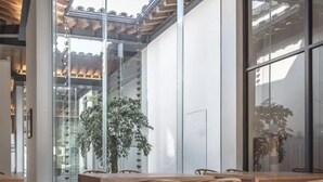 Un intérieur moderne avec un plafond en bois, de grandes fenêtres et un coin repas doté de meubles en bois.