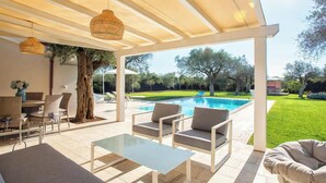 Un espace extérieur aménagé avec une terrasse, une piscine, des sièges et une pergola.