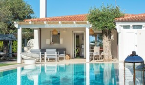Un espace piscine agrémenté d’une pergola, de chaises longues et d’un coin salon abrité.