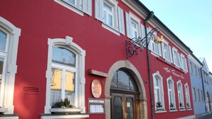En rød bygning med et skilt, der siger "Hotel Kronen", og en klokke over døren.