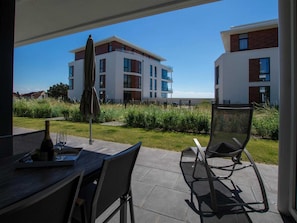 A patio area with a table, chairs, and a bottle of wine.
