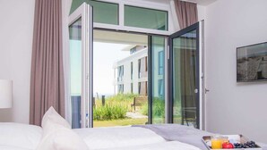 Una camera d'hotel con un letto, un vassoio per la colazione e vista su un edificio e del verde circostante.