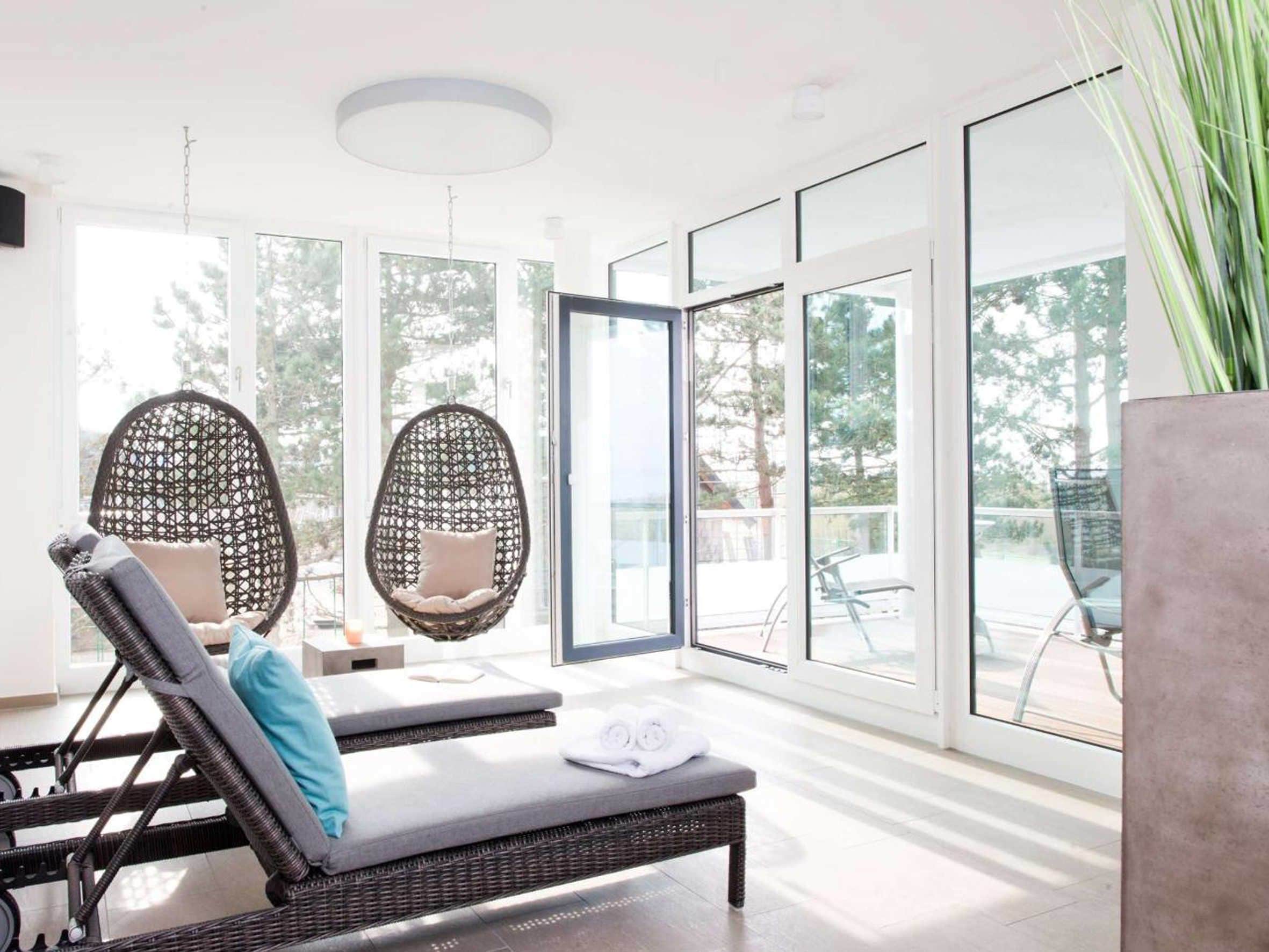 A modern room with large windows, wicker lounge chairs, and a small table.