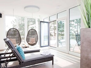 A modern room with large windows, wicker lounge chairs, and a small table.