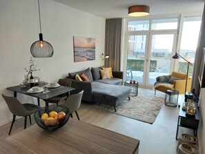 A modern living room with a dining area, a sofa set, a coffee table, and a large window with a view.