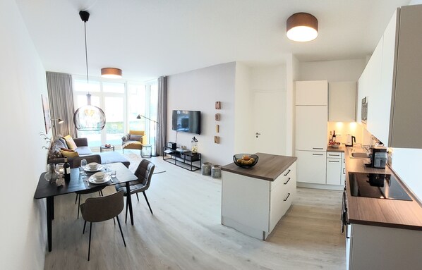 A modern apartment with a dining area, kitchen, and living space.
